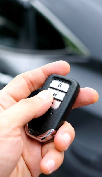 Man hand holding the car remote, he push the remote control to open the car door