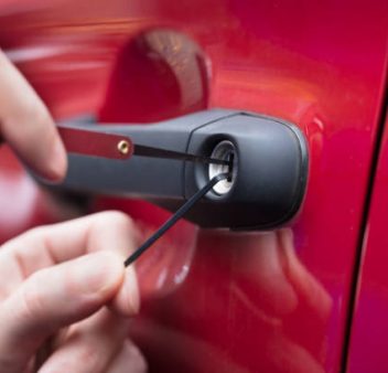 Close-up Of A Human Hand Opening Red Car's Door With Lockpicker